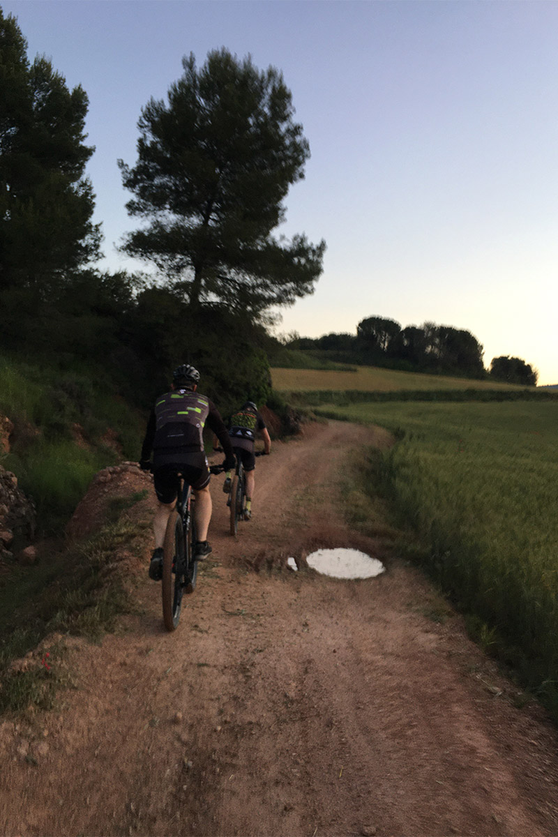 dos ciclistas en bici de montaña esquivando un charco en un camino